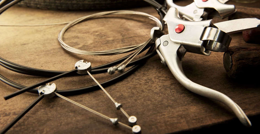 Homme de dos vérifiant le levier de frein d'un Solex posé sur béquille dans une cour pavée, lumière naturelle de fin d'après-midi